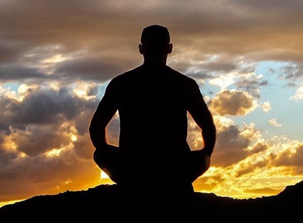 Silhouette of man sitting in lotus position watching the sunset.