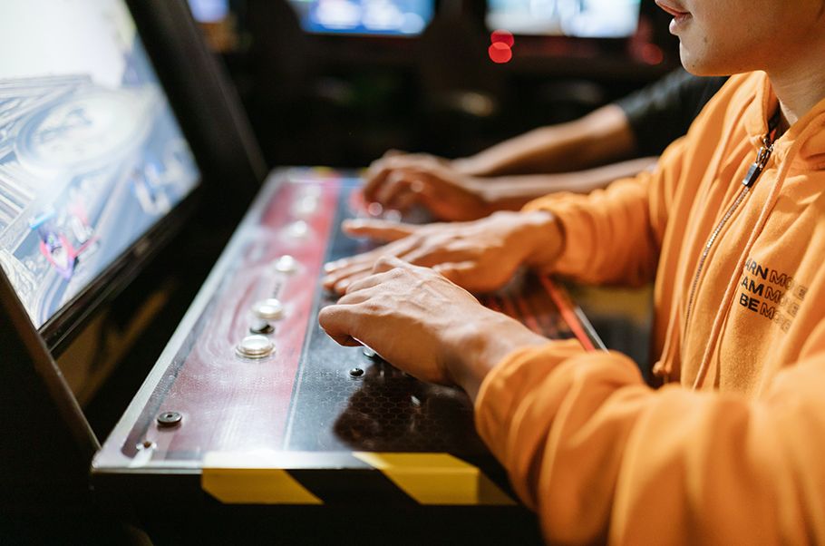 Closeup of someone playing an electronic keyboard while looking at a video game onscreen.