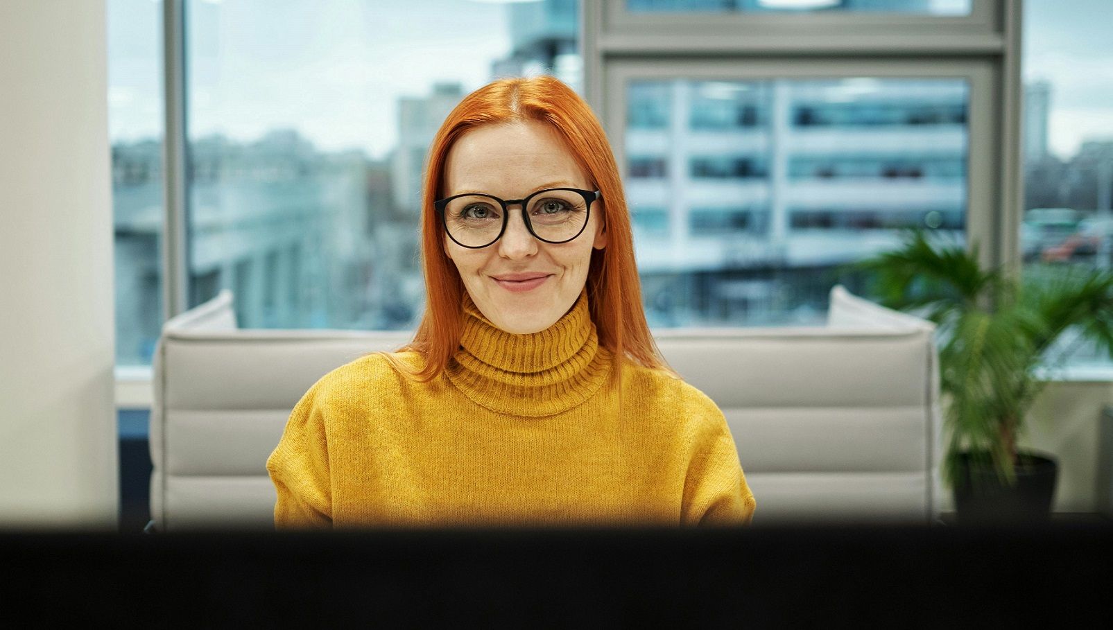 smiling female with glasses sitting behind a desk
