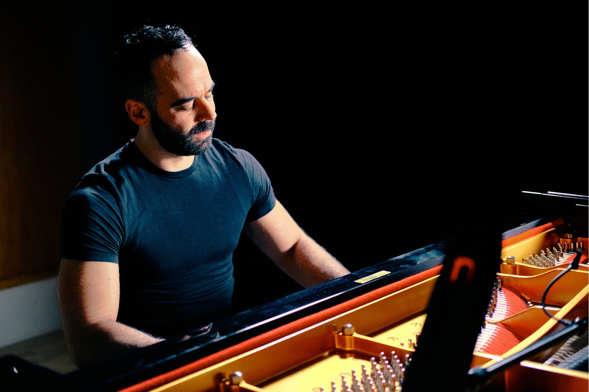 Adam Tindler playing a grand piano.