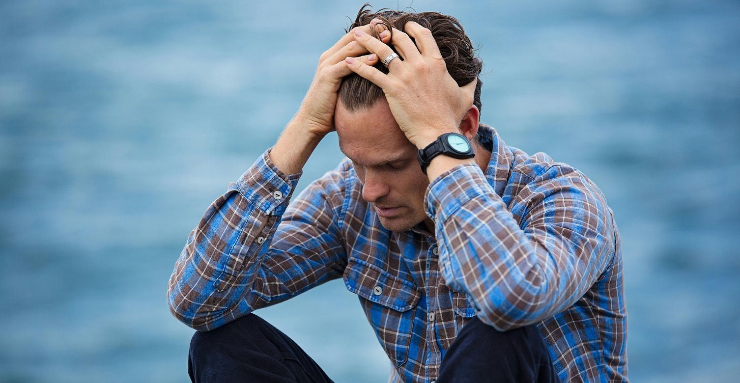 man sitting with head in hands.