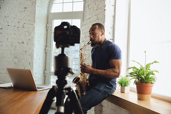 Musician playing saxophone during online concert at home isolated and quarantined.