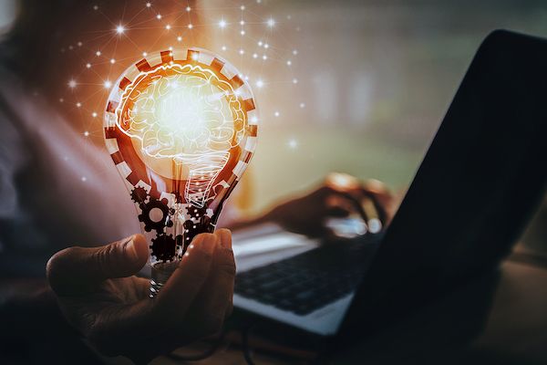 Business women holding an artistically conceptual light bulb with sparks surrounding it.