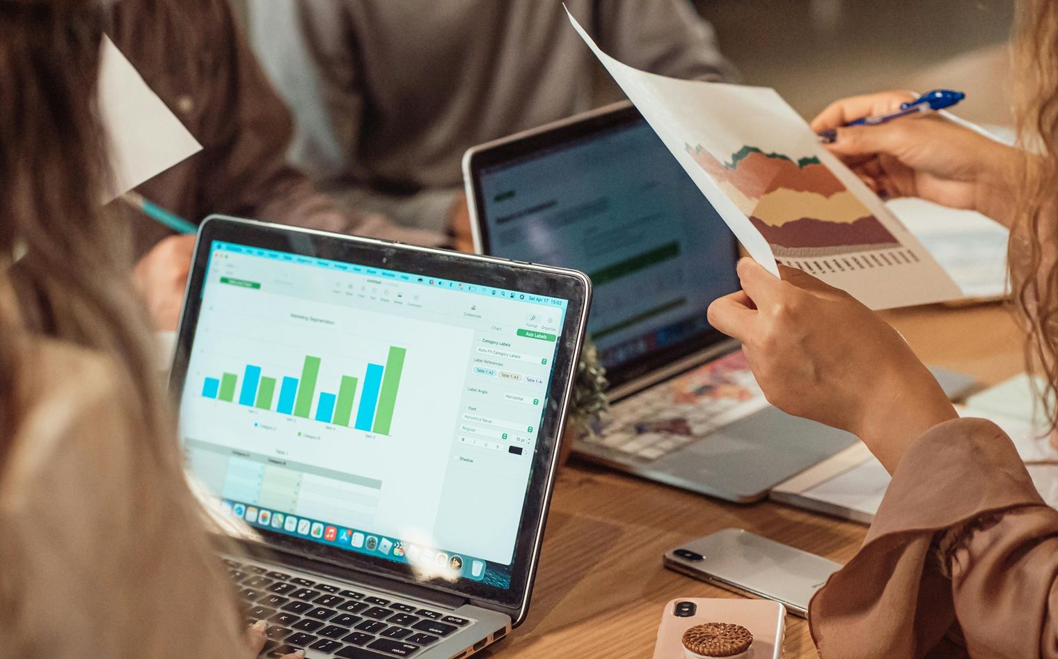 meeting with people looking at data and graphs on laptops and printouts