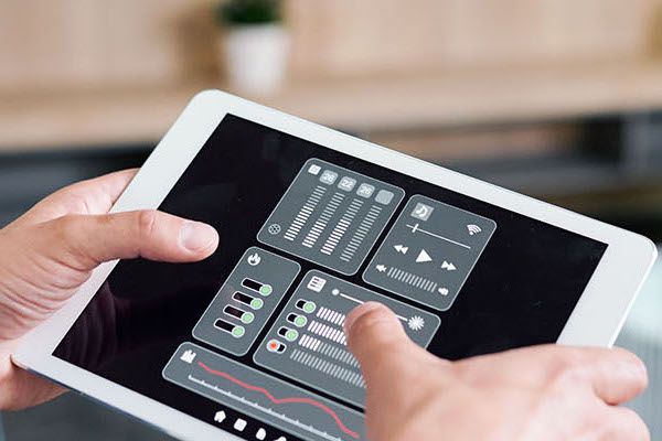 Hands of young man holding tablet with smart remote control system.