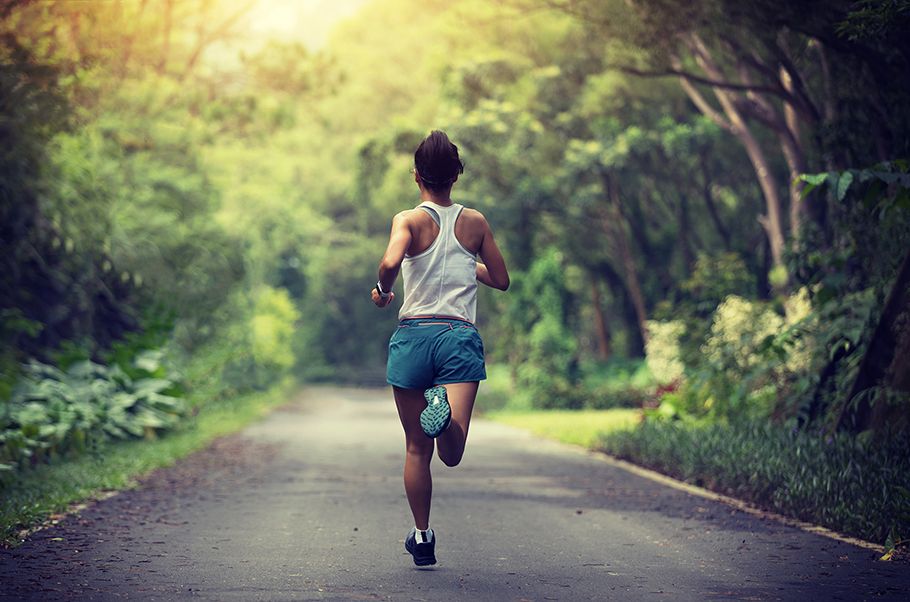 Woman running a trail through a park as seen from behind.