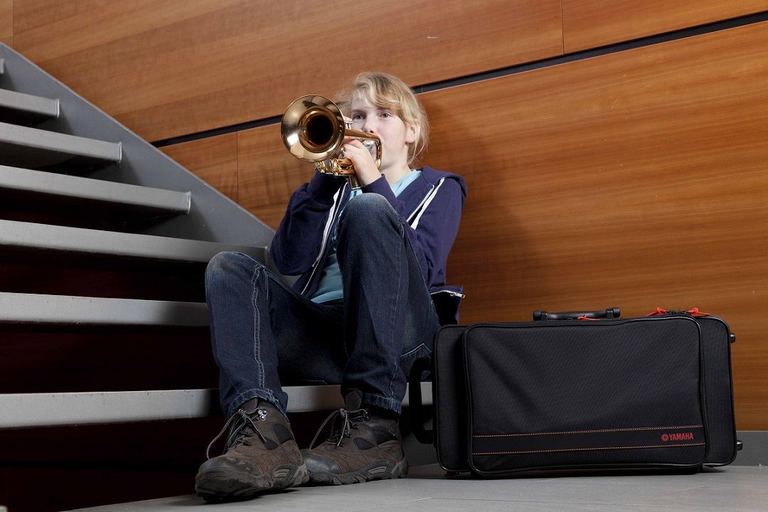 female student practicing trumpet in stairwell