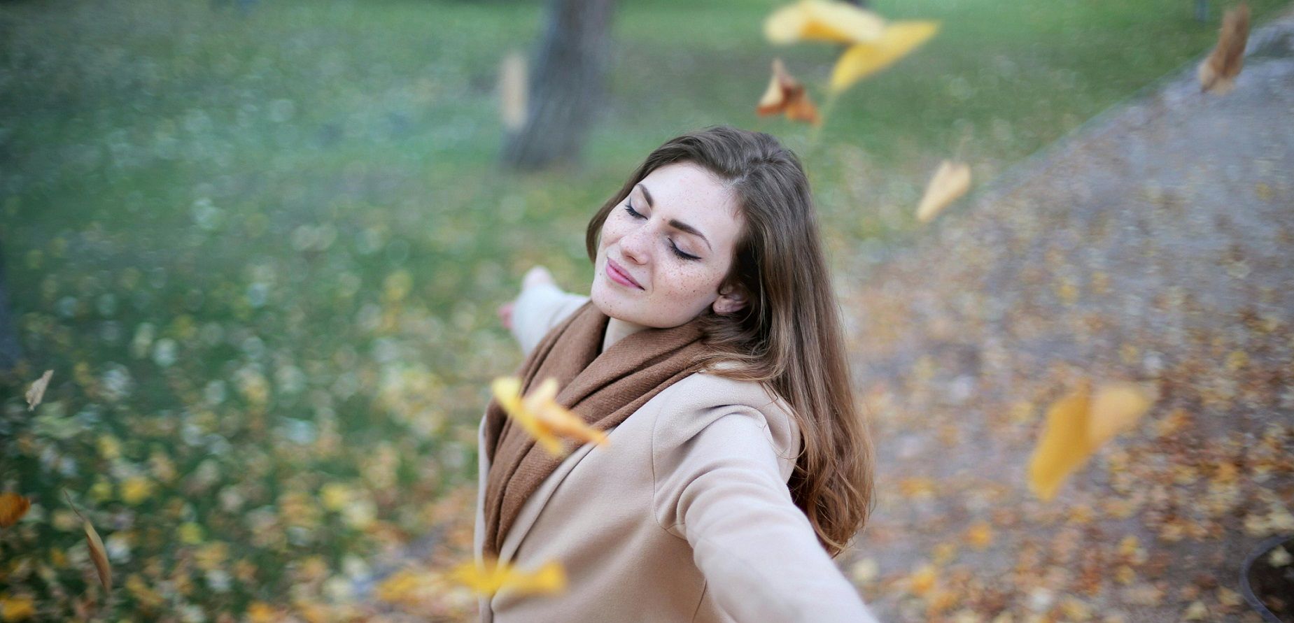 woman standing outdoors with eyes closed and arms outstretched