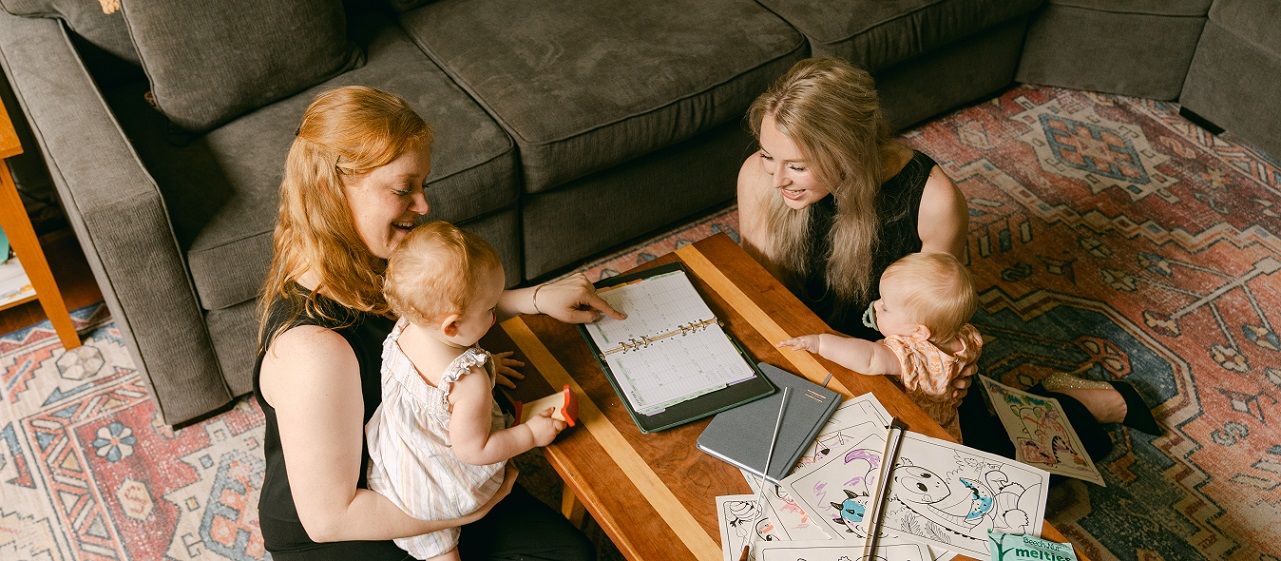 Alexandra Blaine and Annie Ray sitting around coffee table with their daughters
