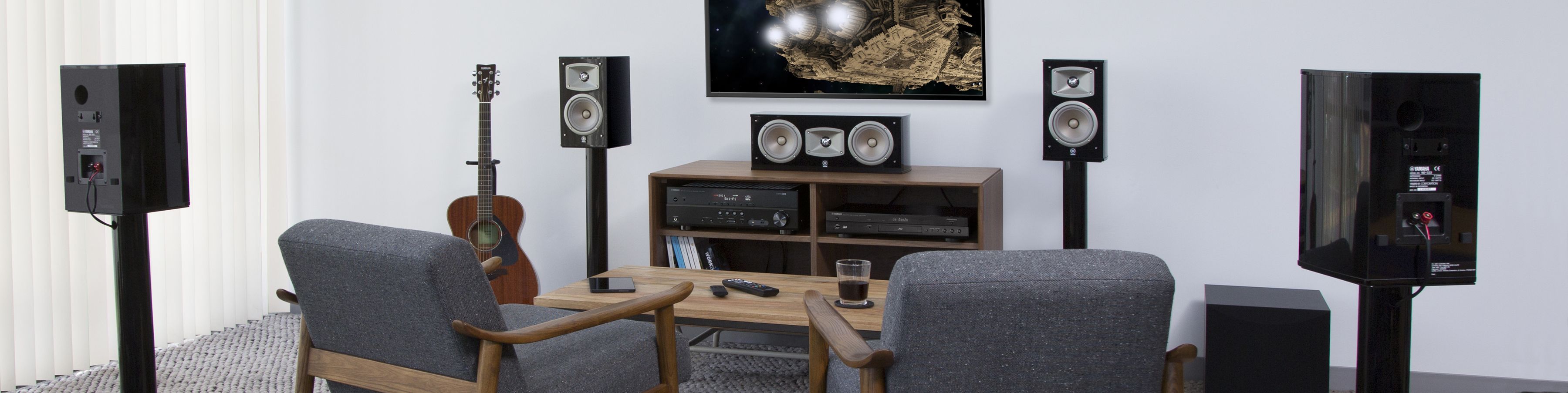 Living room set up with home theater components and chairs facing TV screen.