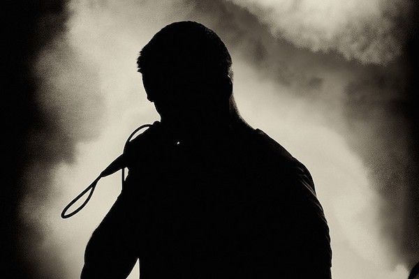 Silhouette of the singer holding microphone and singing on the stage during rock and roll concert.