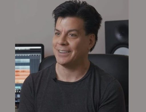 Man smiling for camera with home studio in background.