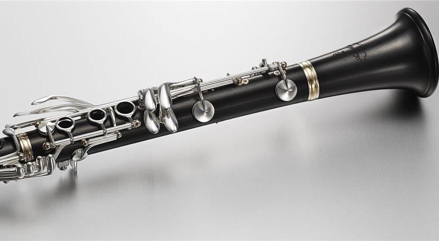 Closeup of a portion of a wooden clarinet on flat surface.