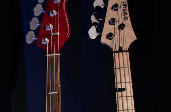 Closeup of two electric bass guitar necks.