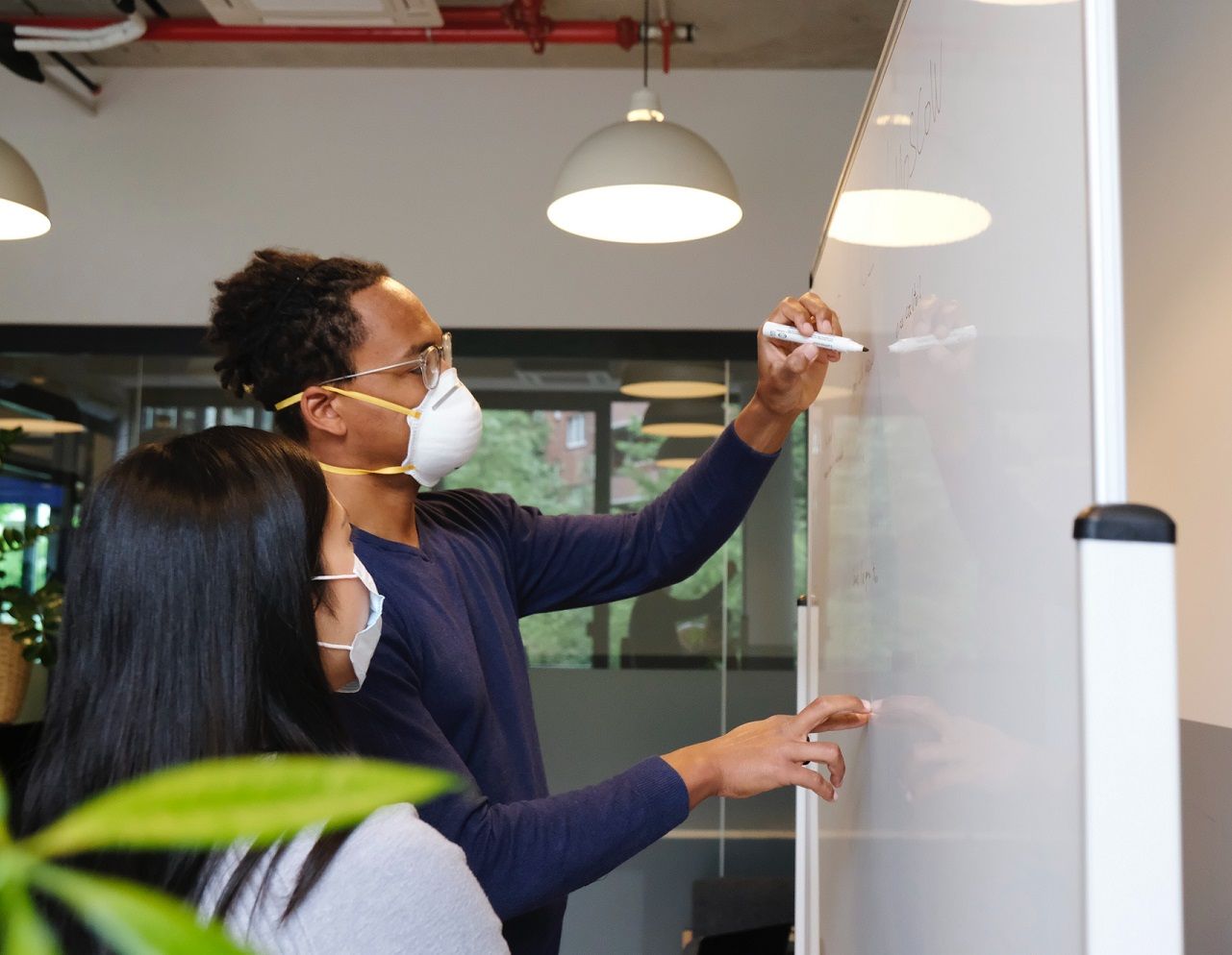 teacher with student -- both wearing masks -- at white board