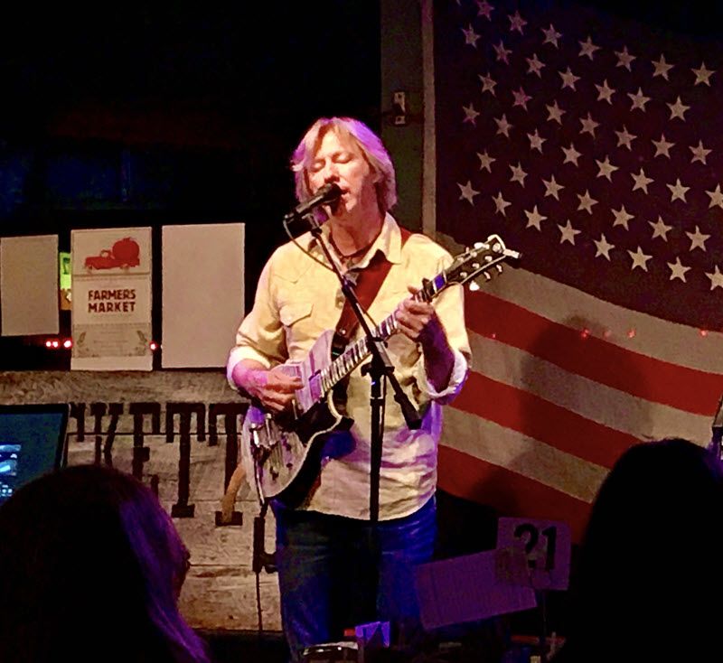 Man on stage playing guitar and singing.