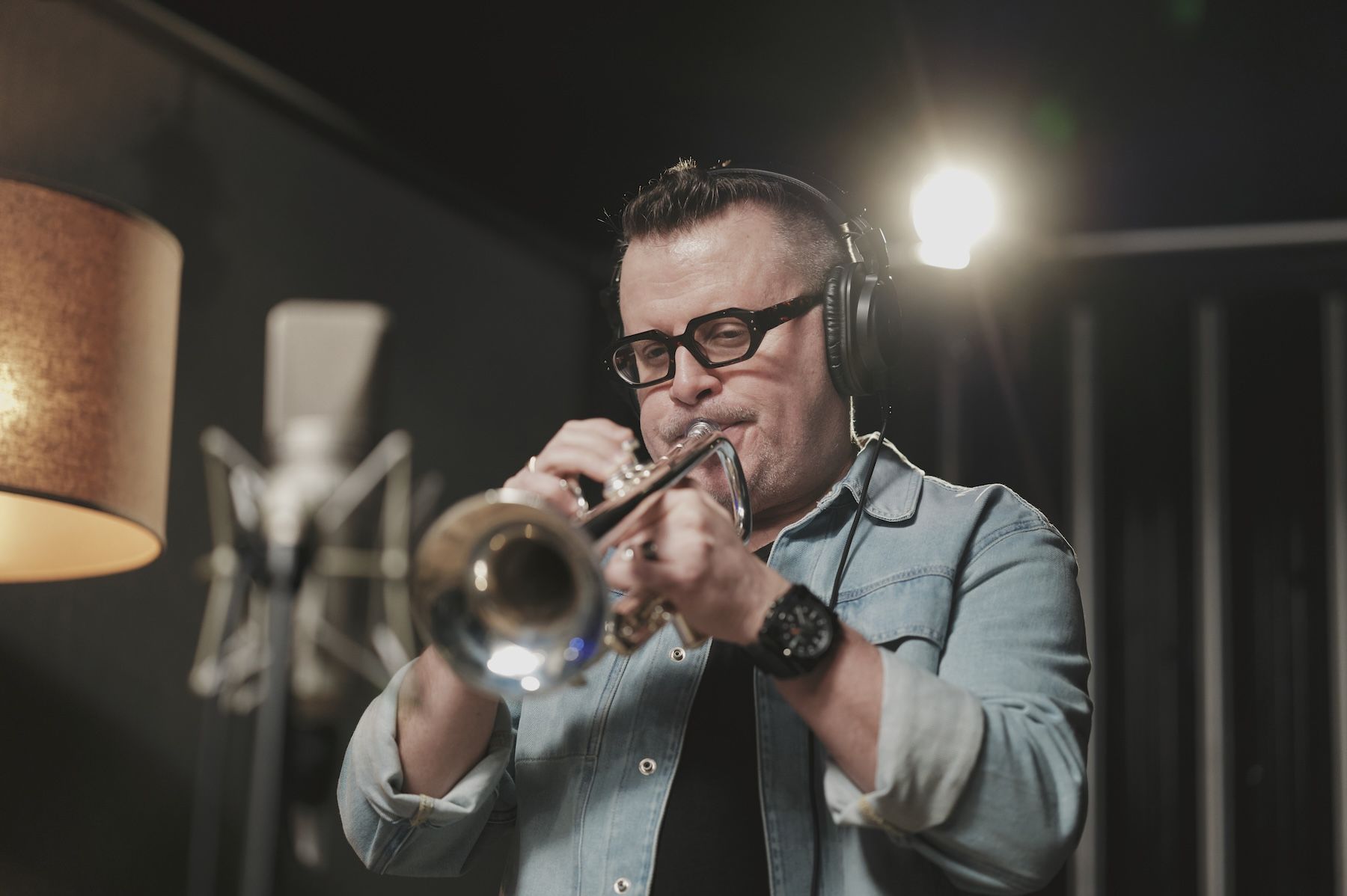 Hero image, man in blue shirt playing trumpet.