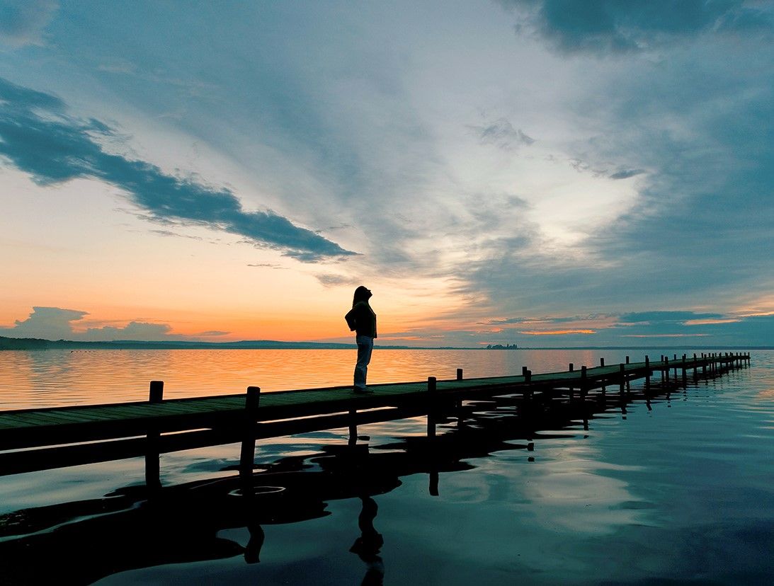 Someone watching a sunset from a long dock.