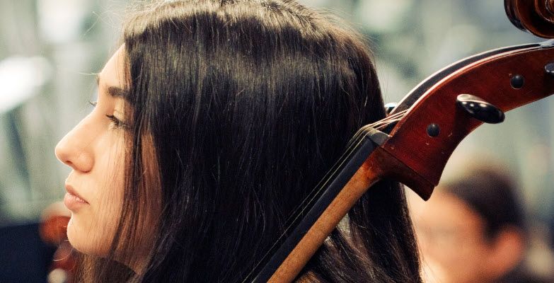 Closeup of young women holding a large string instrument.