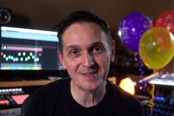 Robert Dudzic smiling for portrait in studio with monitor and balloons behind him.