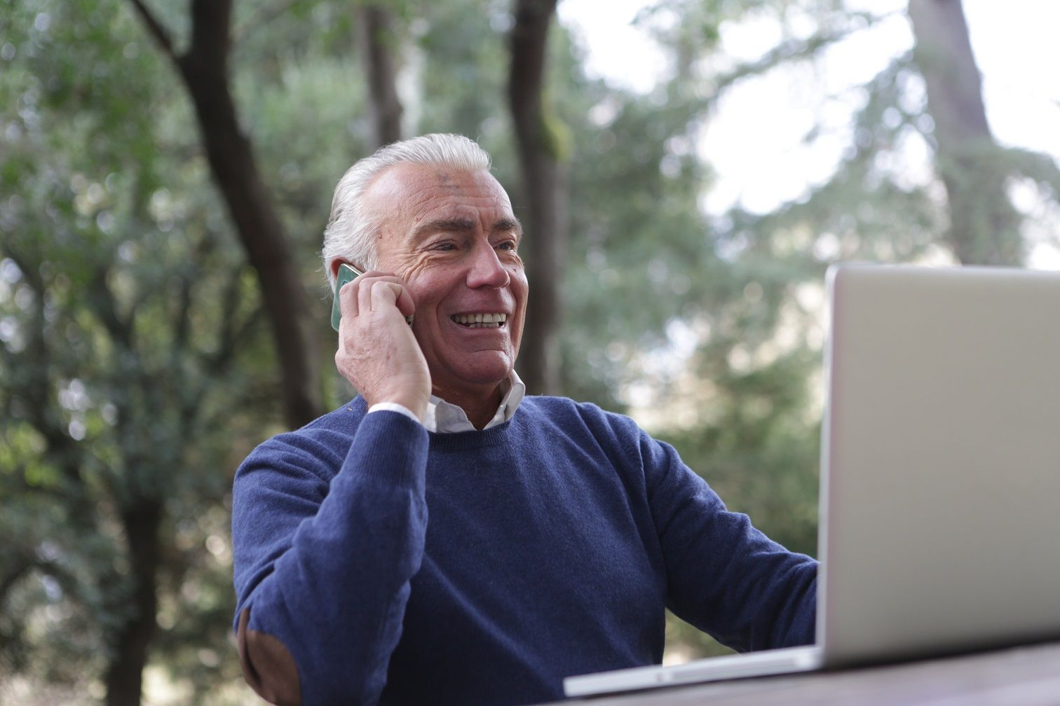 man talking on the phone while sitting in front of laptop