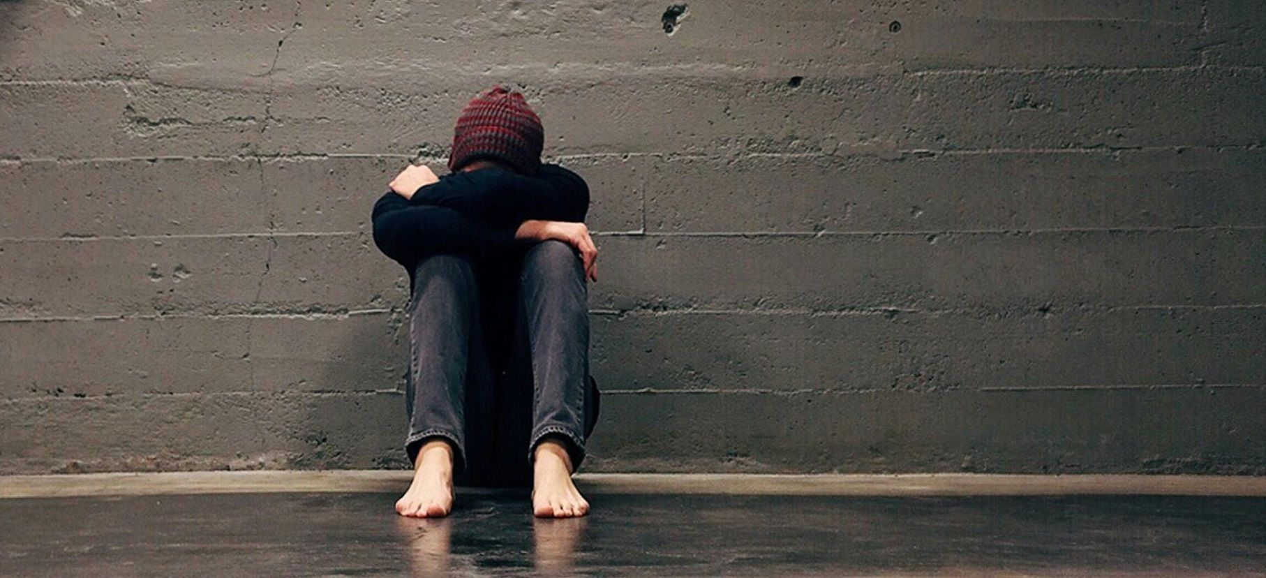 grieving student sitting on ground with head in his arms