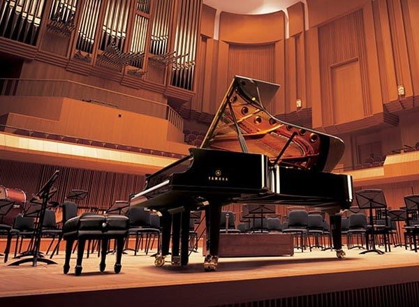 Yamaha Disklavier Concert Grand Piano on a concert hall stage set for performance.