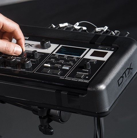 Closeup of someone's hand adjusting the controls of an electronic drum kit.