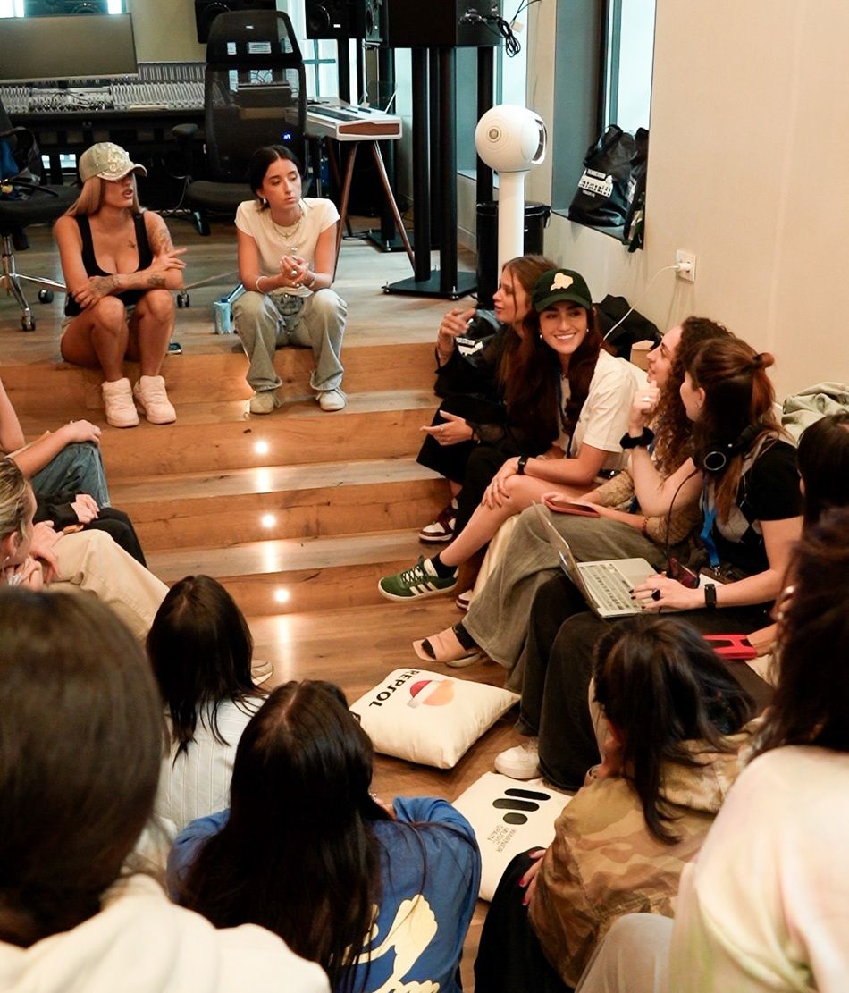 two women sitting on a stair talking to a group of women