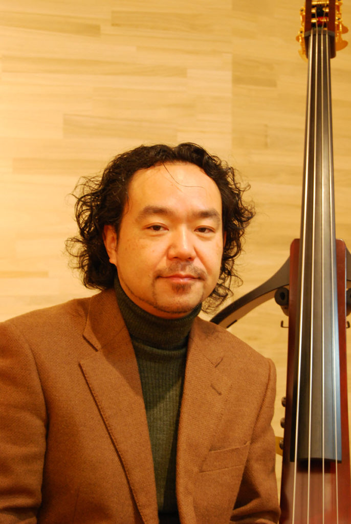 A man posing in front of a Yamaha SILENT bass.