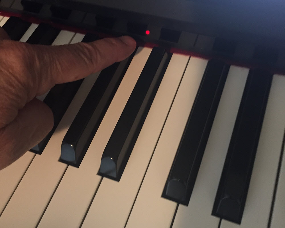 Photo of finger pointing to a light above a keyboard.