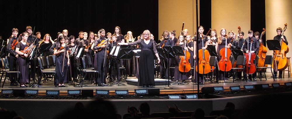 A school orchestra taking a bow onstage.