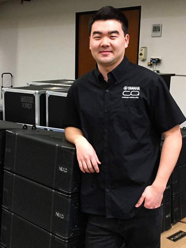 Picture of author - a young man in a logo'd short sleeve shirt leaning on the packing cases for the equipment.