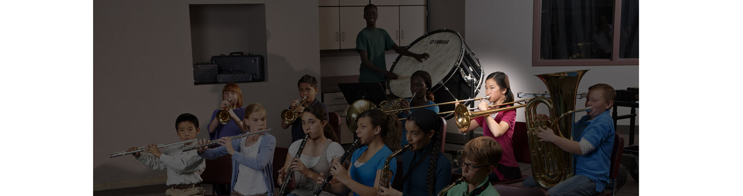 Group of elementary school age children in band practice with a spotlight highlighting the female trombone player.