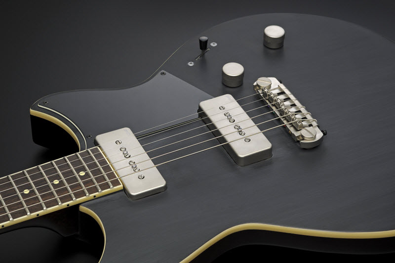 Body of a black electric guitar with silver details lying face-up to show the pickups.