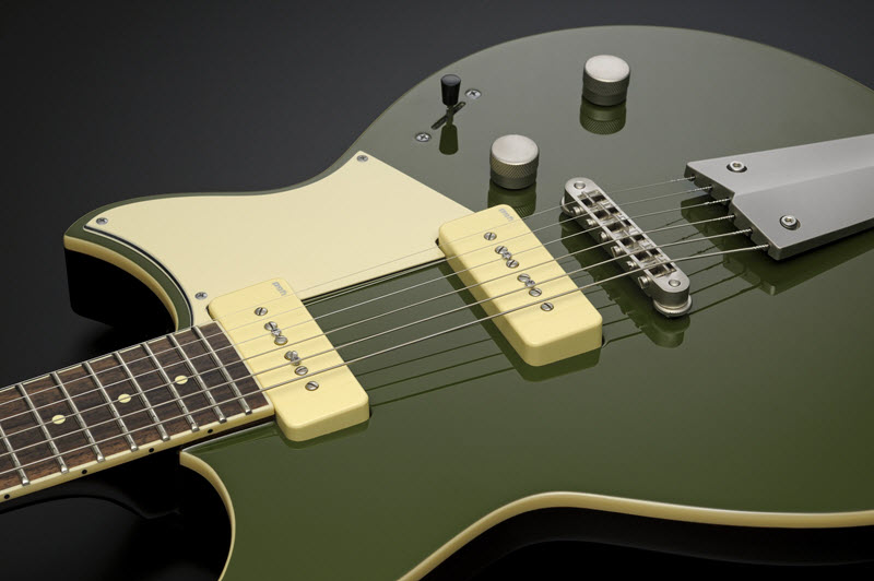 Body of a green and yellow electric guitar lying face-up to show the pickups.