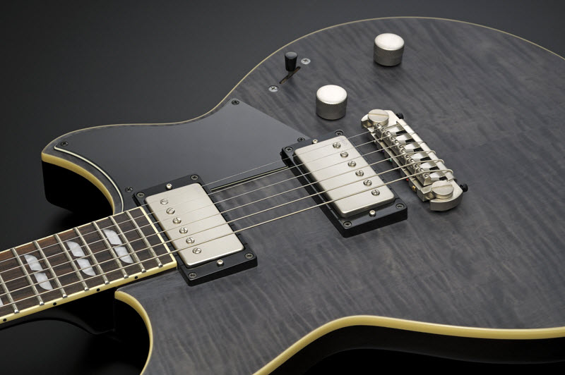 Body of a dark gray electric guitar lying face-up to show it's pick-ups and pick guard.