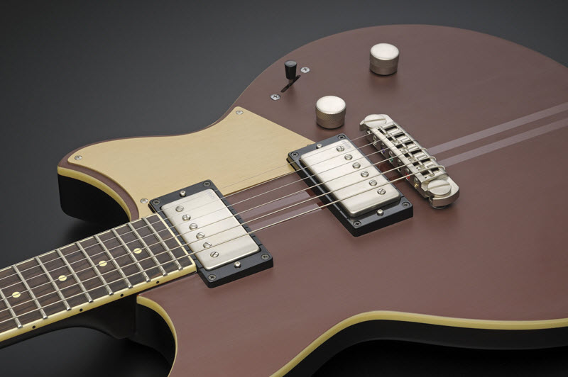 Body of a brown and beige electric guitar lying face-up to show it's pickups.