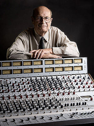 Older gentleman standing behind and leaning on a sound board.