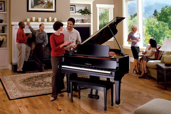 Adults at a party in someone's living room where a player piano is playing itself.