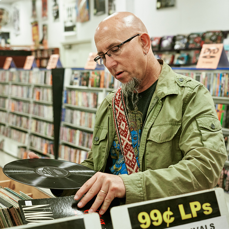 Man in record store looking at a vinyl record.