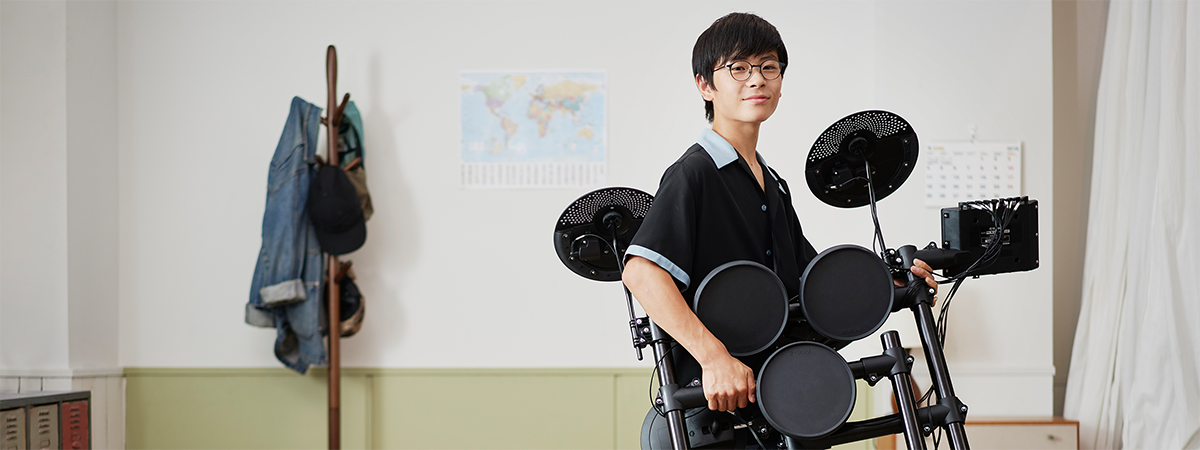 Young man carrying a folded-up electronic drum set.