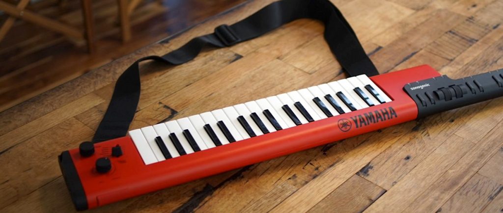 An image of a keytar. It is a portable keyboard that can be held and played like a guitar. There is a strap attached to it.