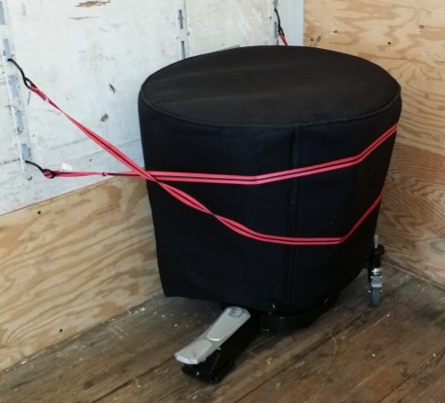 An image of a timpani covered in cloth and secured in the corner of a truck.