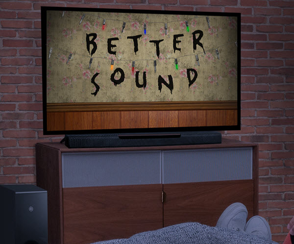 In foreground you see someone's sneakered feet sticking out from under a blanket and in background a large flat screen with a headline on the screen of "Better Sound".