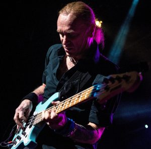 Billy Sheehan on stage playing a bass guitar.