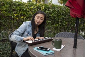 Woman playing Yamaha Pianica flat on a table.