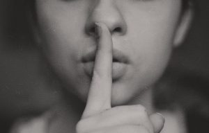 woman holding index finger to lips 