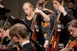 two students playing electric bass 