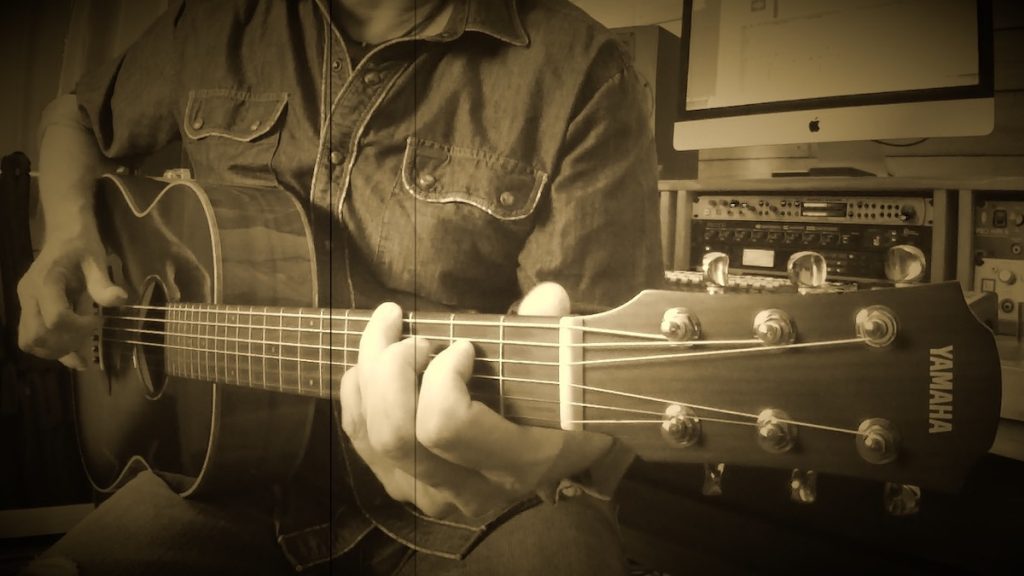 Man playing guitar with vintage-style photo filter.